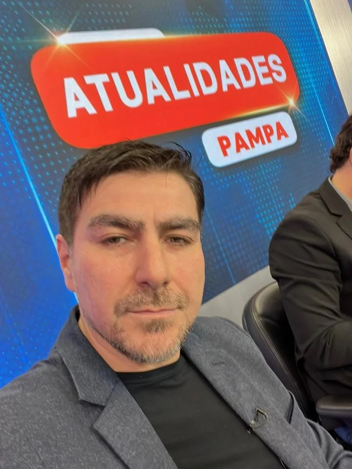 Fernando Zanuzo no estúdio, diante do cenário do programa Atualidades Pampa, da TV Pampa