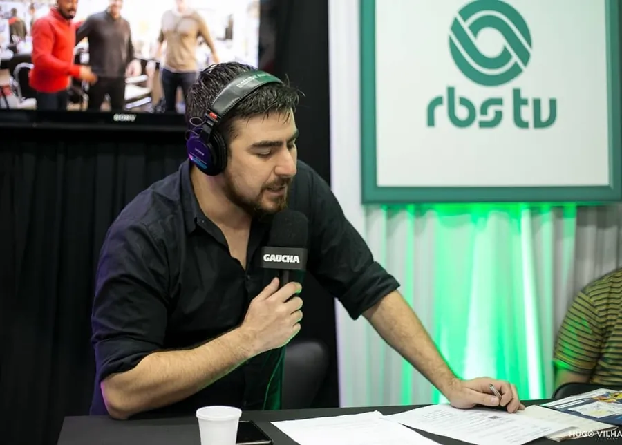 Fernando Zanuzo com fones de ouvido, ao microfone da Rádio Gaúcha, durante transmissão