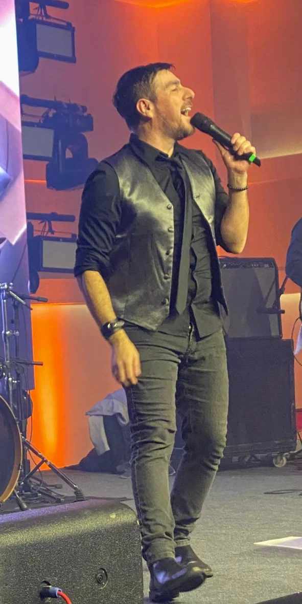 Fernando Zanuzo cantando ao microfone no palco