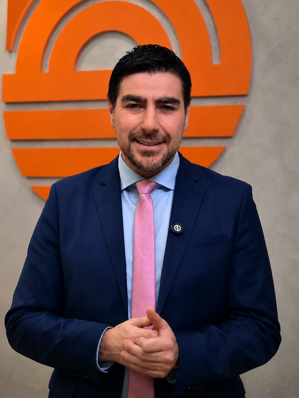 Fernando Zanuzo em frente ao logotipo da emissora, em ambiente de televisão